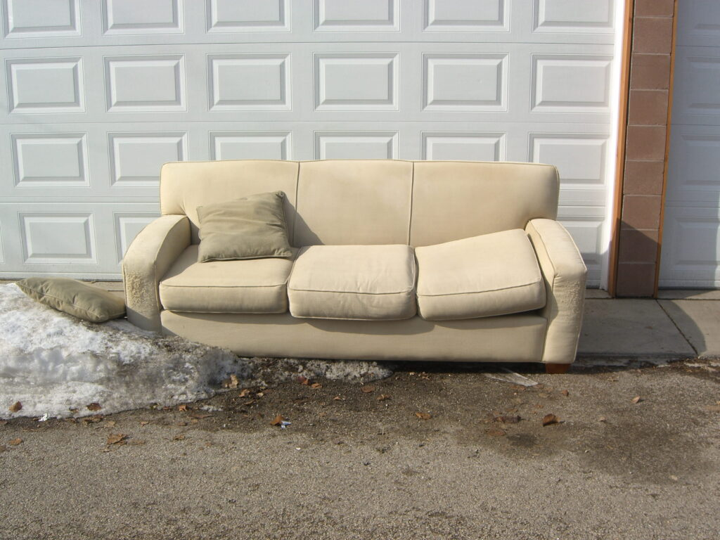 beige-couch-abandoned-on-asphalt-near-garage-door-2026-09-22-10-18-10-utc (1)
