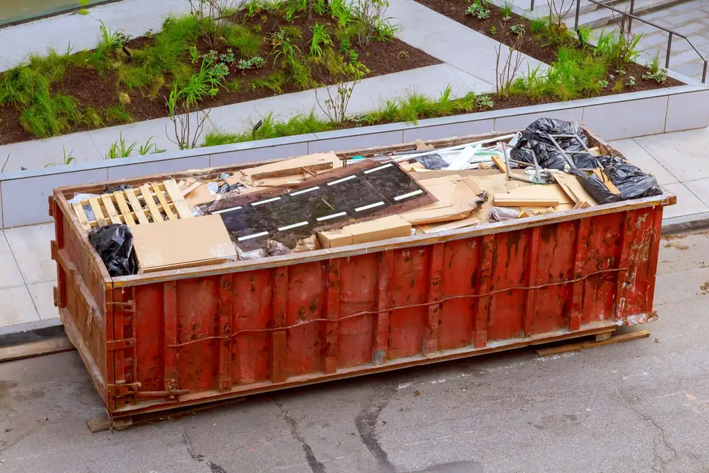 Full bin of wood and renovation debris on a paved lot